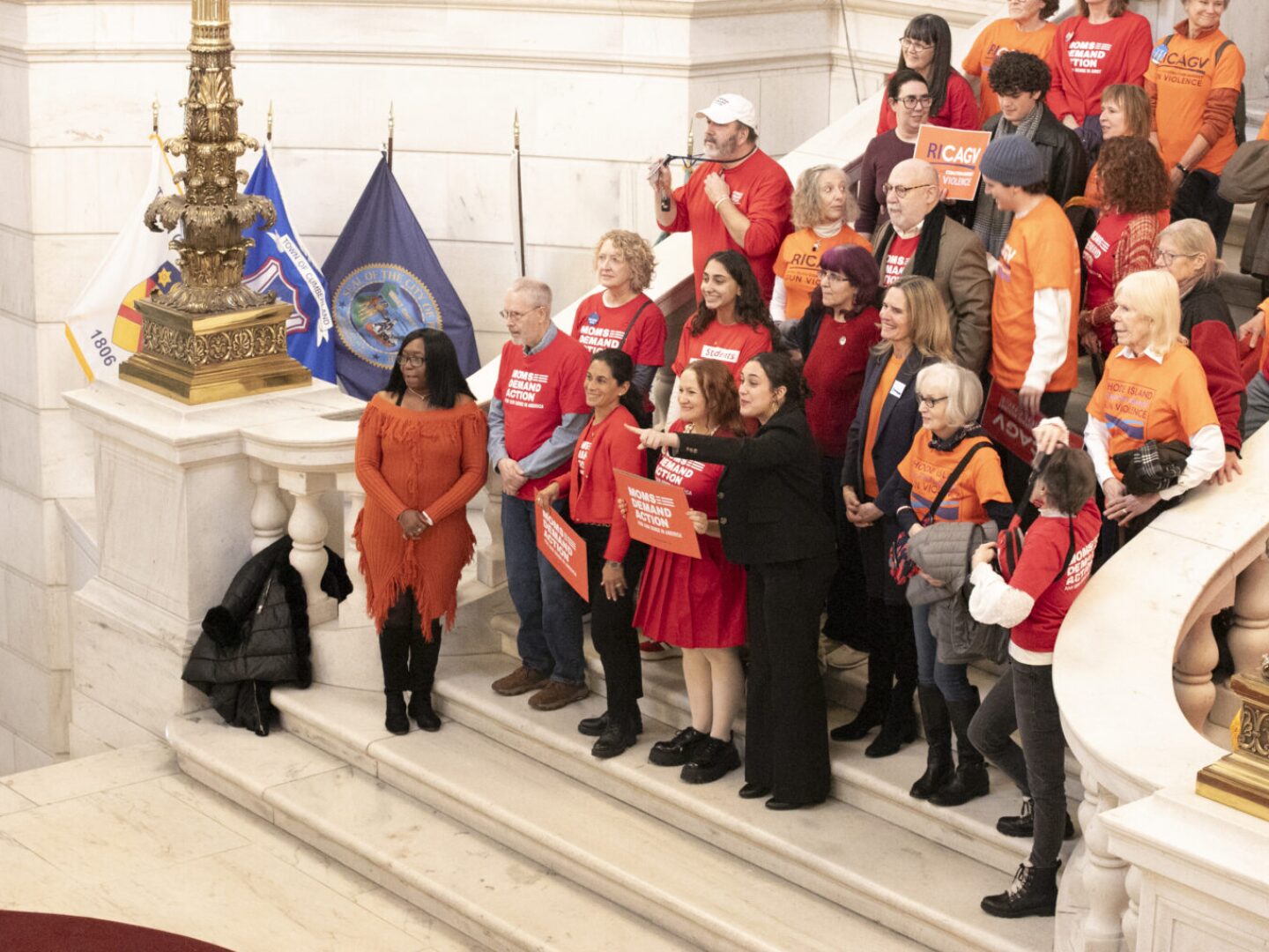 Mia Tretta, center, is seen pointing at a camera as gun legislation advocates gather on the steps of the rotunda in the Rhode Island State House on Tuesday, Feb. 11, 2025.