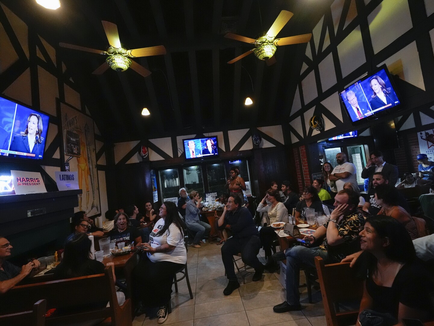 FILE - People watch TV screens showing a debate between Democratic presidential nominee Vice President Kamala Harris, right on screen, and Republican presidential nominee former President Donald Trump, at Sports Grill Kendall, where the Miami-Dade Democratic Hispanic Caucus had organized a watch party, Tuesday, Sept. 10, 2024, in Miami.