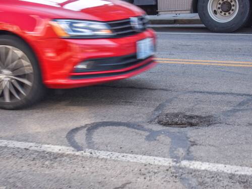 A car drives perilously toward a pothole on Point Street in Providence.