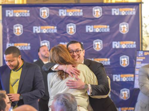 General Treasurer James Diossa shares a hug ahead of a press conference detailing the state’s plans to accommodate international travelers who will visit New England this summer for the 2026 FIFA World Cup.