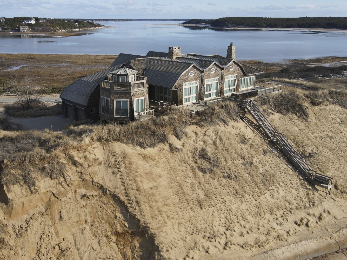 A home sits atop of a sandy bluff overlooking a beach in Wellfleet, Mass, Wednesday, Feb. 2, 2022.