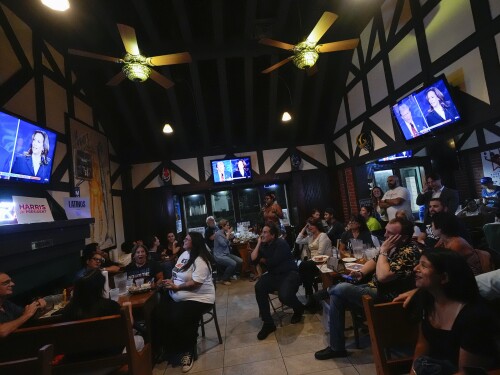 FILE - People watch TV screens showing a debate between Democratic presidential nominee Vice President Kamala Harris, right on screen, and Republican presidential nominee former President Donald Trump, at Sports Grill Kendall, where the Miami-Dade Democratic Hispanic Caucus had organized a watch party, Tuesday, Sept. 10, 2024, in Miami.