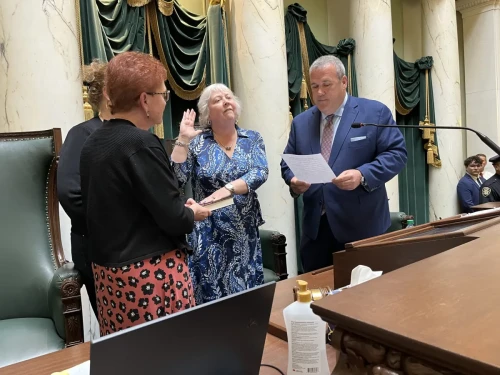 Val Lawson takes the oath of office as Senate president in April from Secretary of State Gregg Amore, as her sisters, Kathleen McCabe and Kerry Lawson, look on.