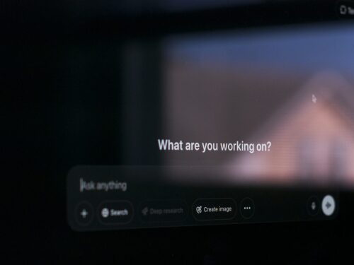 A computer screen reflects a window and shows the default prompt when opening ChatGPT, a popular generative AI application often credited with igniting the AI boom since its release in 2022.