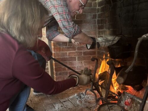 Ashley Hanson of New London, Conn., puts hot coals over the pear chutney while Steven Kornatz of Scituate, R.I., checks on the herbed rice during a Colonial kitchen lesson at the home of Ellen L. Madison in Westerly.