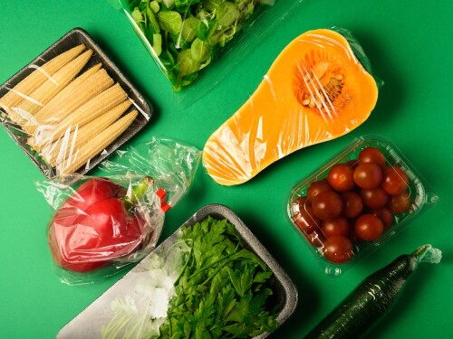 Fresh vegetables in plastic package. Zero waste, recycle concept. Plastic pollution. Green background