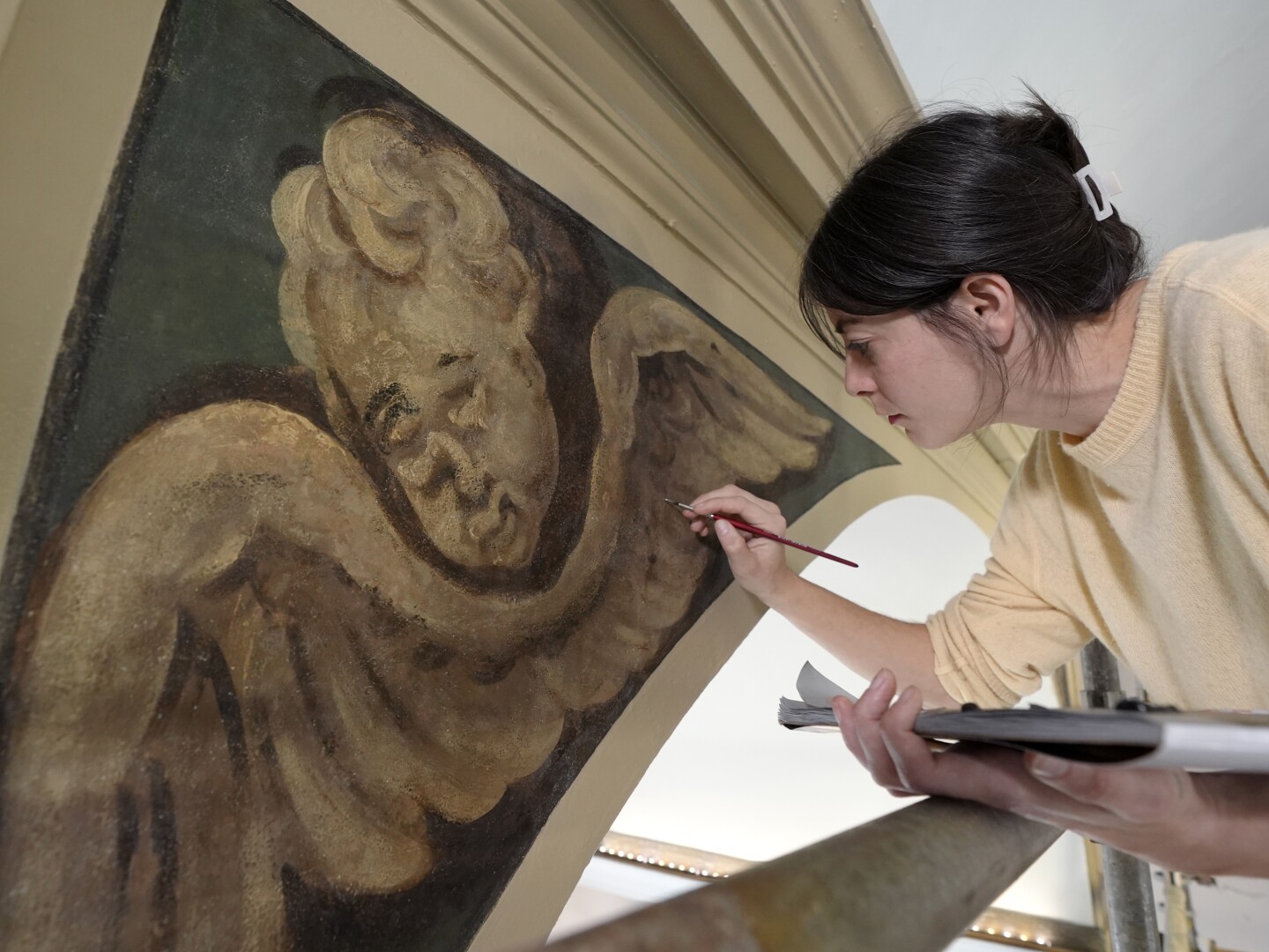 Conservator Corrine Long, of Dover, N.H., restores nearly 300-year-old painted angels on walls of Old North Church, Wednesday, Dec. 18, 2024, in Boston.