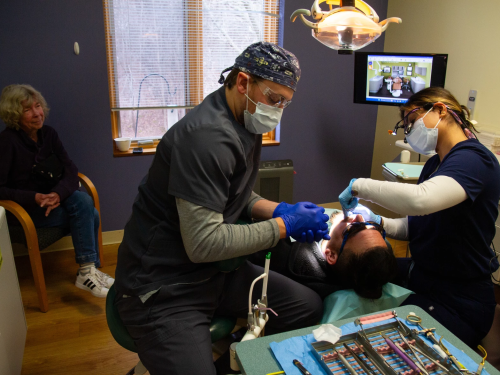 University of New England dental student Shaguftha Pabani, right, and dental assistant Max Hopper, left, help with some fillings for Luis, center, a farmworker from Addison County. Sitting in the corner is Susan Stone, a volunteer Spanish interpreter. This dental care is provided through a partnership between Middlebury Dental Group and Open Door Clinic.