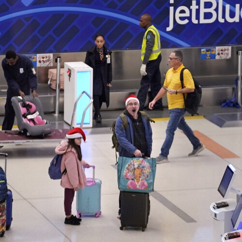 Holiday traveler Julio Henriquez of Canton, Mass., yawns while traveling with his children Marcelo and Amanda at Logan Airport, Friday, Dec. 20, 2024, in Boston.