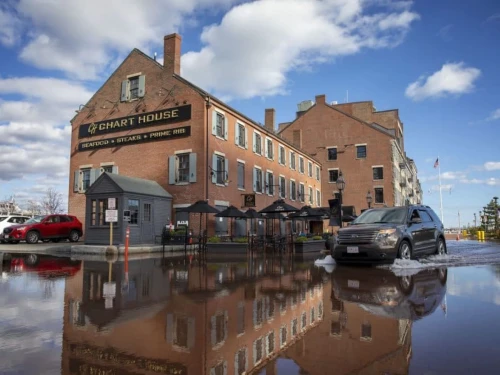 A car drives through flood water by the Chart House on Boston's Long Wharf during a November king tide.