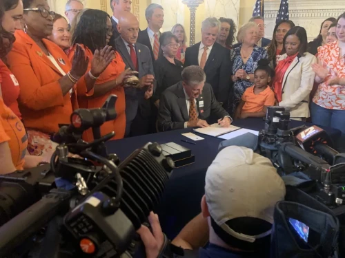 Flanked by gun control advocates, RI Gov. Dan McKee signs a new law that will ban the sale of military-style assault weapons.