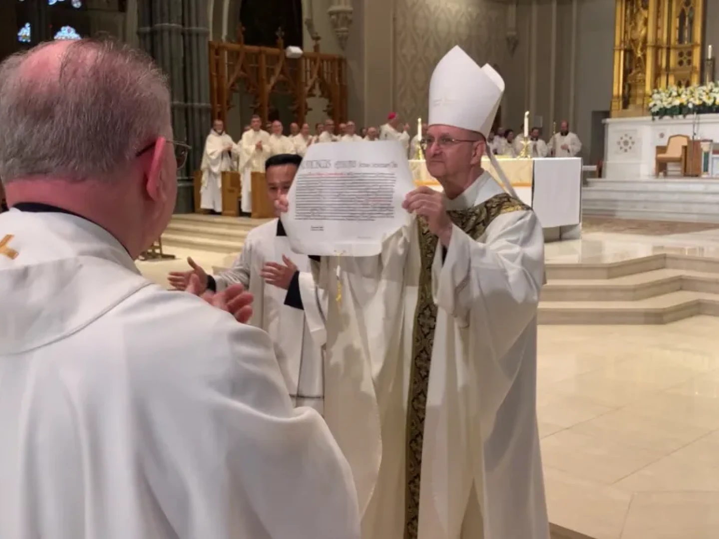 Bishop Bruce Lewandowski holds up the Apostolic Mandate, in which Pope Francis named him 10th Bishop of Providence