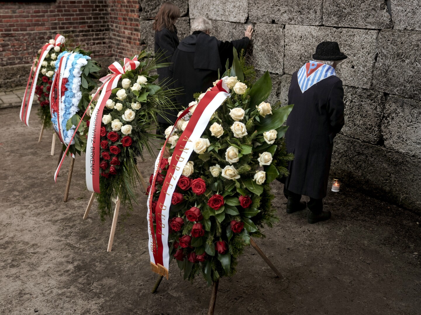 A survivor stands after placing a candle to the Death Wall at the Auschwitz-Birkenau former Nazi German concentration and extermination camp, during a ceremony marking the 80th anniversary of the camp's liberation, in Oswiecim, Poland, Monday, Jan. 27. 2025.