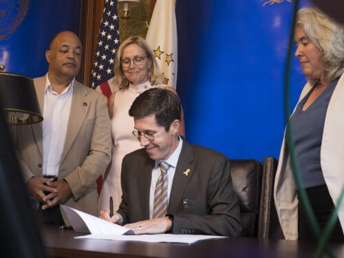 Providence Mayor Brett Smiley signs the fiscal year 2026 budget at his City Hall office on July 15, 2025. Standing from left to right are Providence City Councilors Pedro Espinal, Helen Anthony and Rachel Miller. Anthony chairs the council’s finance committee and Miller is Council President.